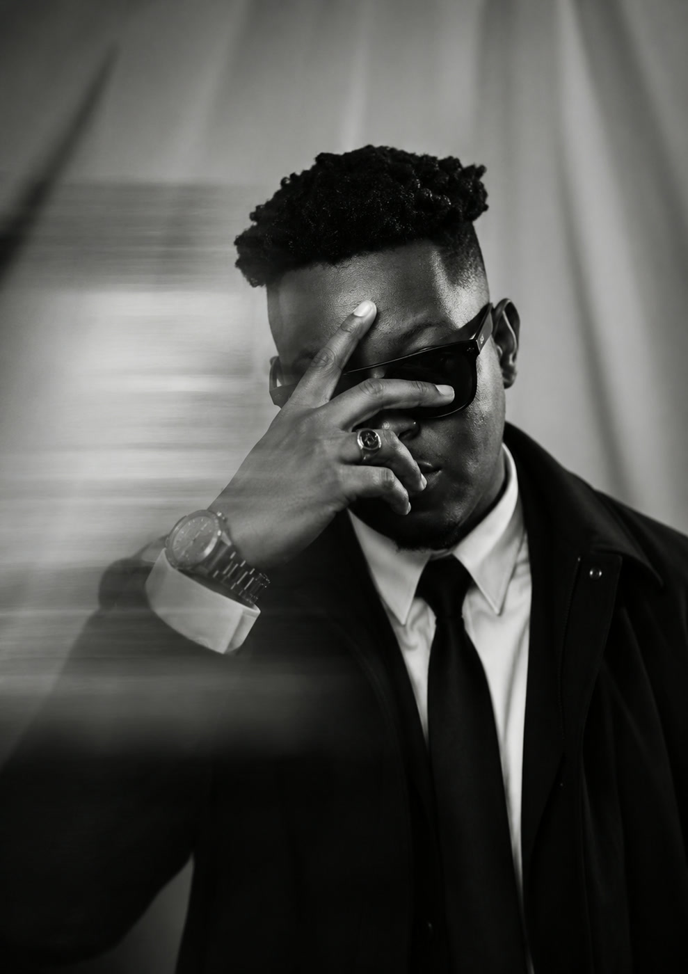 Black-and-white portrait of Promaxx wearing sunglasses and a suit